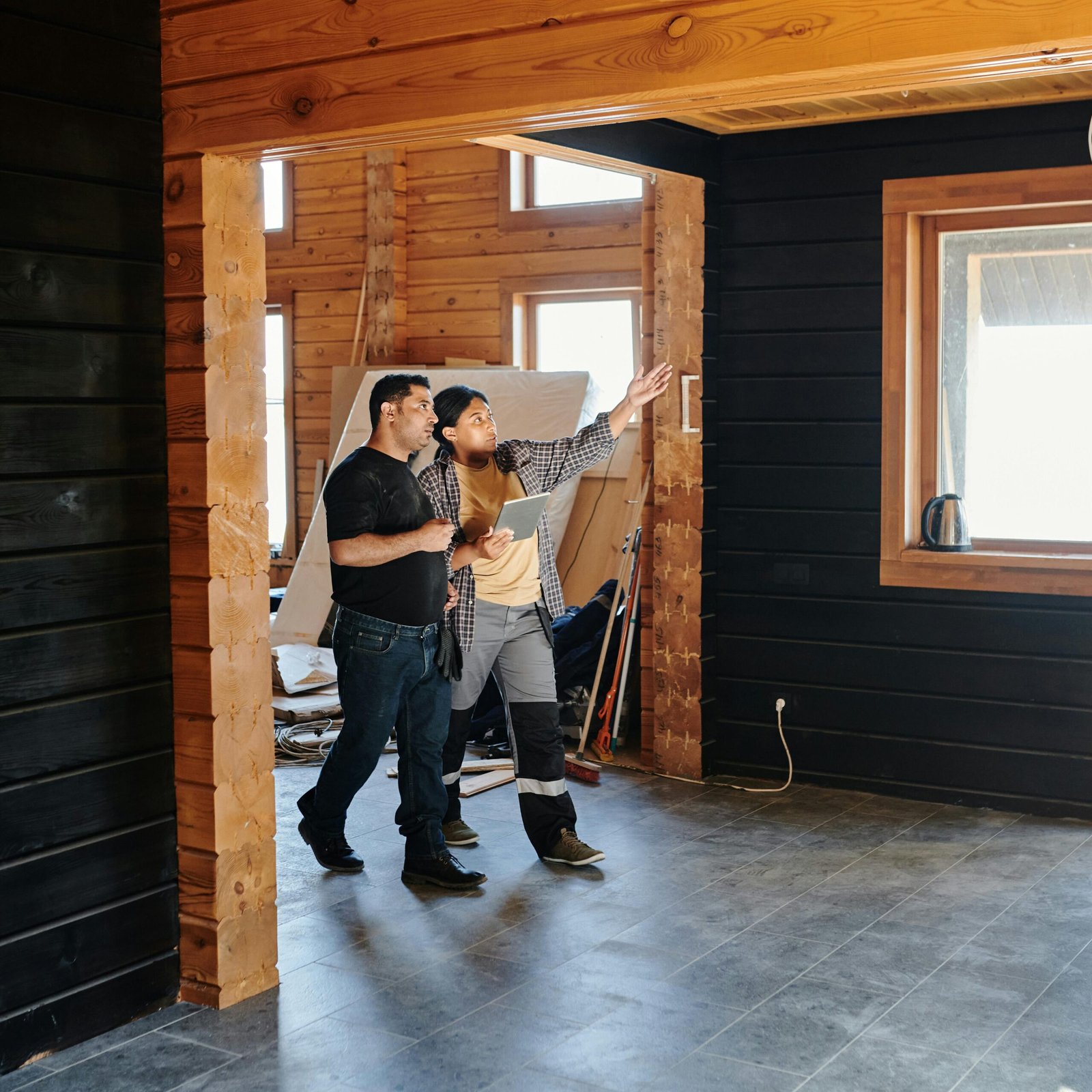 Two adults discussing home renovation in a partially constructed modern wooden interior.